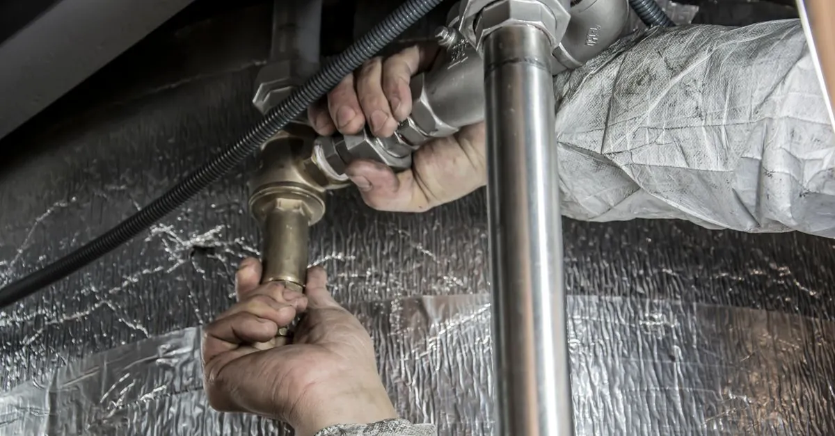 A plumber calculating service costs on a clipboard at a professional workbench.
