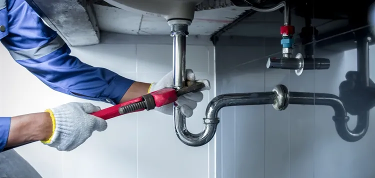 A plumber inspecting industrial pipes in a commercial building during a maintenance check.